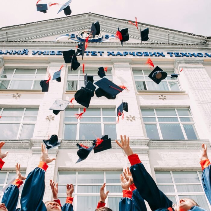 Group of fresh graduates throwing their academic hats in the air